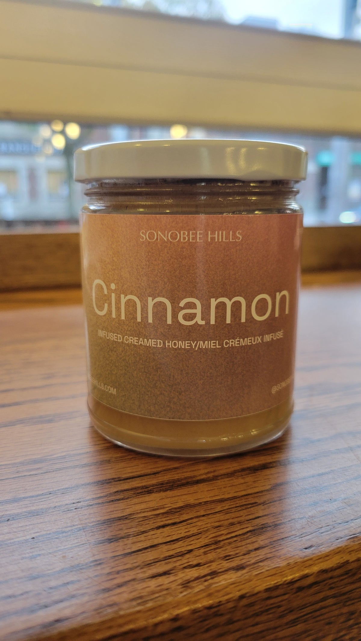 Jar of Sonobee Hills Cinnamon honey on a wooden surface